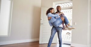 Man carrying a woman walking into their new home